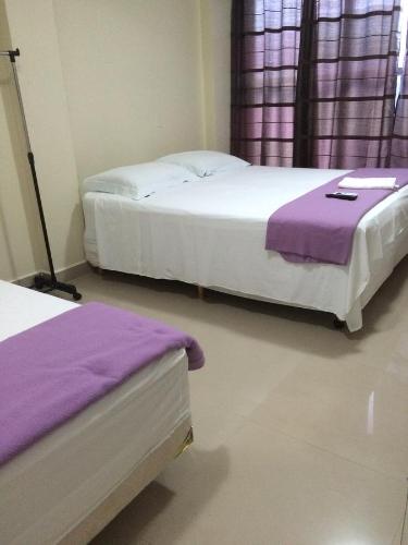 巴西利亚Pousada Verdes Flores的紫色床单的客房内的两张床