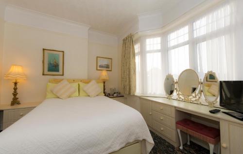 伯恩茅斯Shoreline Accommodation的一间卧室配有一张床、一台电视和镜子