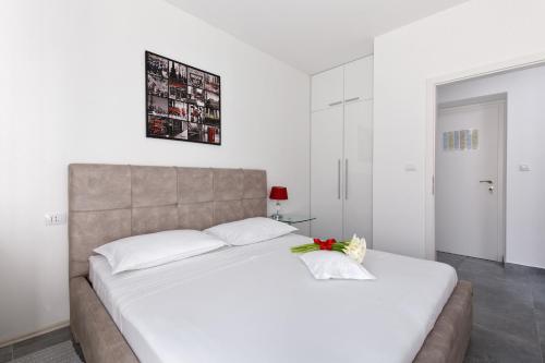 斯普利特卡拉卡雷塔公寓的一间卧室配有一张白色大床,床上有鲜花