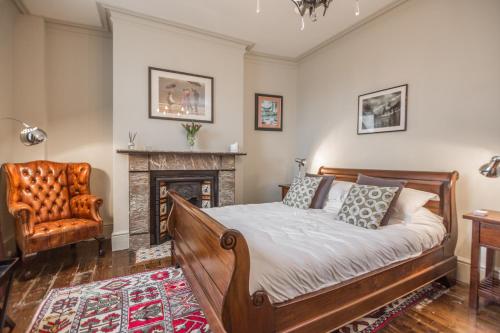阿尔恩茅斯St Valery Boutique Bed + Breakfast的一间卧室配有一张床、一把椅子和一个壁炉