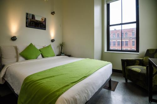 波士顿HI Boston Hostel的一间卧室配有一张带绿色床单的床和一扇窗户。