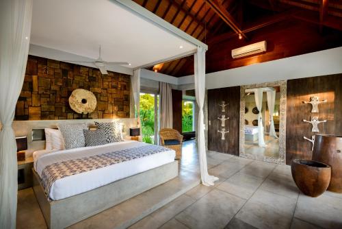坎古伊帕内玛巴厘岛别墅的一间卧室设有一张大床和石墙
