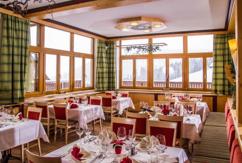 拉赫塔尔Monarchia Park的餐厅设有白色的桌椅和窗户。