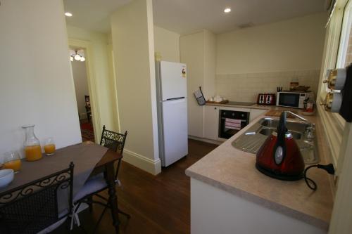 霍巴特安尼斯花园度假屋的厨房配有桌子和白色冰箱。