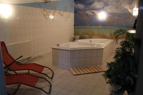 维斯马Hotel Mecklenburger Mühle Garni的带浴缸、椅子和绘画的浴室