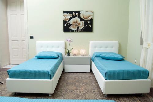 皮亚扎-阿尔梅里纳B&B Villa Roma的卧室内的两张床,配有蓝色枕头