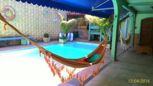 阿拉亚尔-杜卡布Suítes Casa Verde的庭院内的吊床,设有游泳池