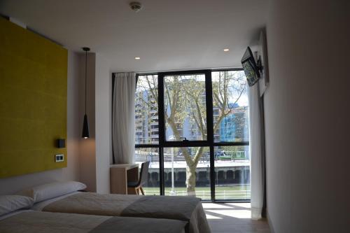 毕尔巴鄂毕尔巴鄂广场酒店的一间卧室设有两张床和大窗户