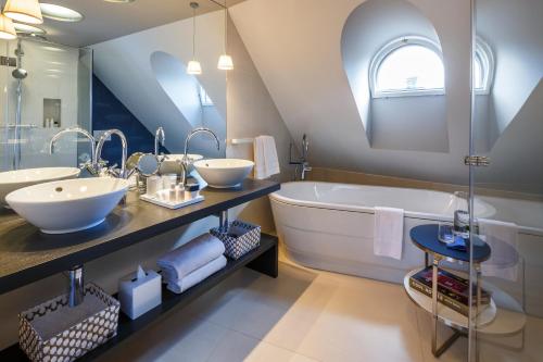 苏黎世西霍夫酒店的浴室配有大浴缸、两个盥洗盆和大镜子
