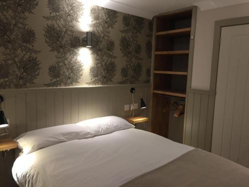 欧文The Harbour Guest House的一间卧室配有一张带白色床单和壁纸的床