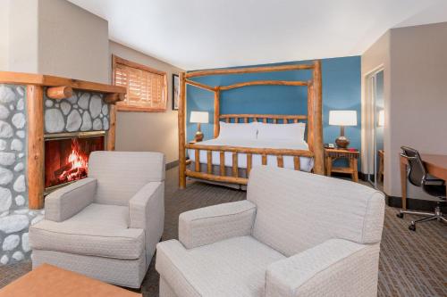 大熊湖大熊湖山林小屋假日酒店&度假村的一间卧室配有一张床、两把椅子和一个壁炉