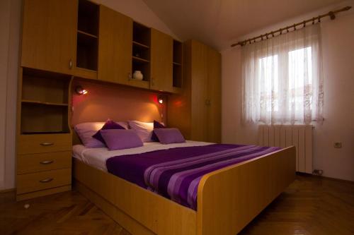 克尔克Apartments Dario的一间卧室配有一张带紫色床单的床和窗户。