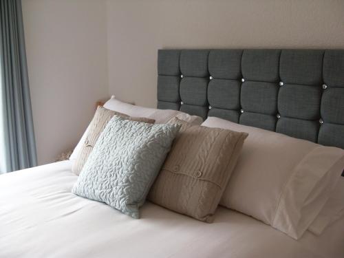 哈雷克Dol Aur - Room Only的一张带白色枕头的床和一个灰色垫子床头板