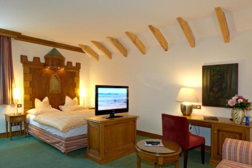 萨维尔纳让家酒店的一间卧室配有一张带电视和书桌的床。