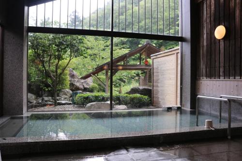 那须盐原市大黑屋板室温泉旅馆的透过大窗户可欣赏到花园景色的游泳池