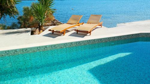 阿马林索斯波尔图埃维亚精品酒店 的两把椅子和一个毗邻大海的游泳池
