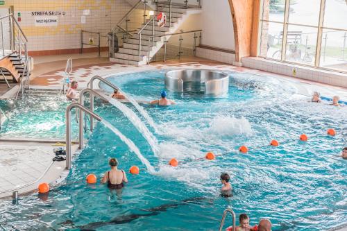 托伦Hotel i Aquapark Olender的一群人在室内游泳池玩耍