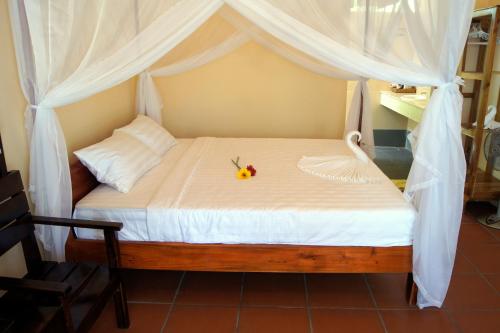 富国金沙滩别墅酒店的一张带白色天篷的床,上面有花