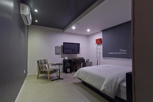 光州五月酒店的一间卧室配有一张床、一张书桌和一台电视。