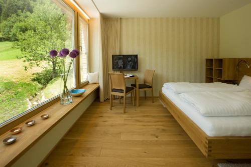 多恩比恩Hotel Alpenrose Ebnit的一间卧室配有一张床、一张桌子和一个窗户。