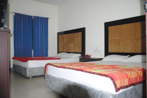 库克斯巴扎Hotel Sea Alif的两张位于酒店客房的床,配有蓝色窗帘