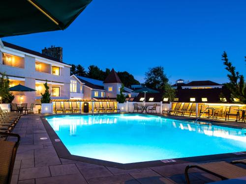 奥甘奎特梅朵梅尔度假酒店的一个带桌椅的夜间游泳池