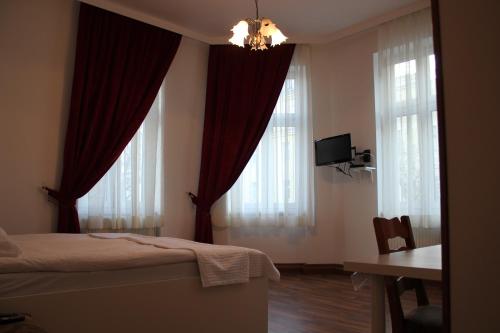 维也纳阿内维也纳酒店的一间卧室配有红色窗帘、一张床和一张书桌