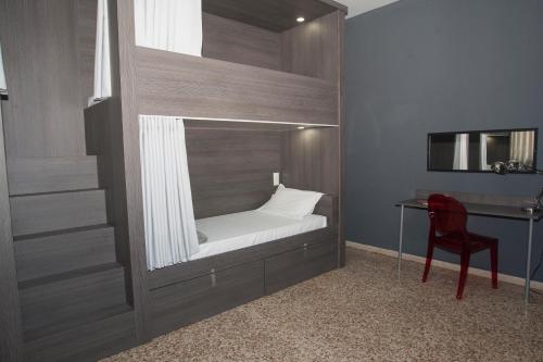 瓦伦西亚Quart Youth Hostel & Apartments的一张位于带桌子和椅子的房间内的床铺