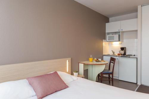 拉罗谢尔Appart'City Classic La Rochelle Centre的一间卧室配有一张床和一个小厨房