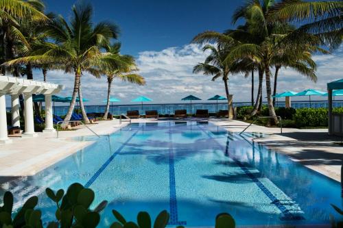 棕榈滩布雷克棕榈海滩酒店的棕榈树和大海的游泳池