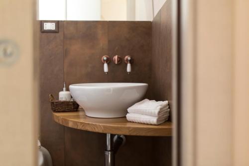 马泰拉吉奥公寓的木制架子上设有白色碗水槽的浴室