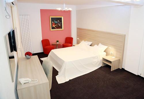 布加勒斯特Parliament Square的酒店客房带白色的床和红色椅子