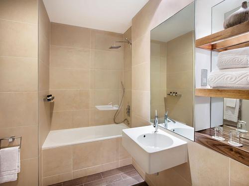 卡迪夫Leonardo Hotel Cardiff的一间带水槽、浴缸和镜子的浴室