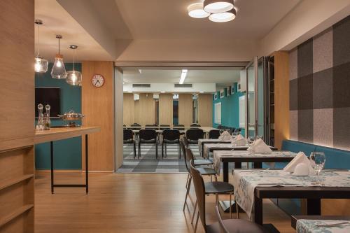 斯科普里城市公园酒店的一间带桌椅的餐厅和一间候客室