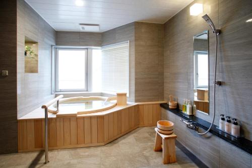 登别祝之宿登别格阑饭店的大型浴室设有浴缸和淋浴。