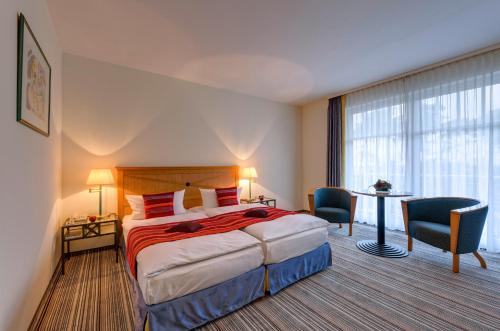 奥斯赛拜-屈隆斯博恩海蓝玉酒店的酒店客房带一张床、一张桌子和椅子