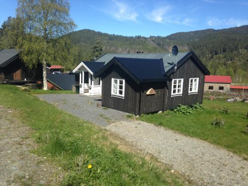 TuddalTuddal Hyttegrend, GAMLESTUGU, Telemark的一座黑色房子,在田野上有一个蓝色的屋顶