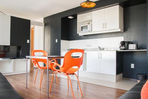 蒙得维的亚Rentline Apartamentos - Sunline的厨房配有2把橙色椅子和桌子