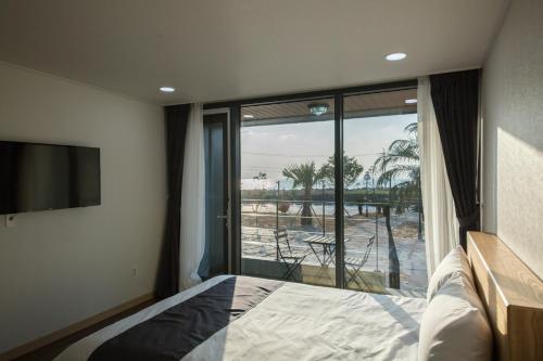 西归浦市Ĵ劳姆度假村的一间卧室设有一张床和一个大型玻璃窗