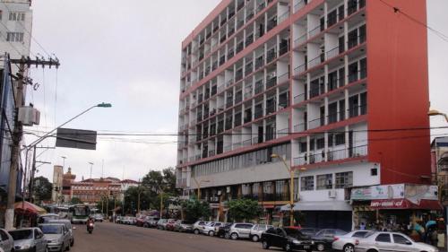 马瑙斯阿茹里卡巴8号公寓的城市街道上一座红色的建筑,有汽车停放