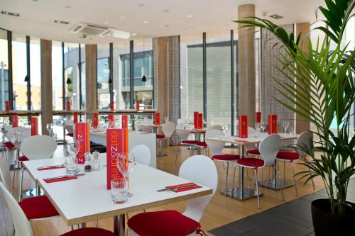 卡迪夫加的夫安睡者酒店的一间设有白色桌子和红色椅子的餐厅