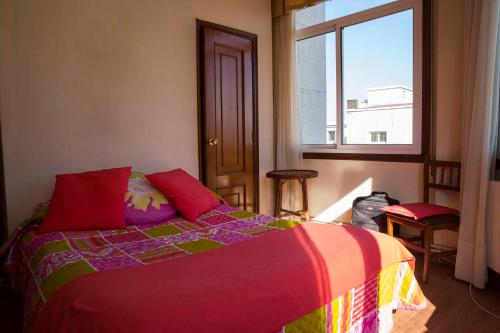 维戈Hostal A Pedra的一间卧室配有一张带红色枕头的床和一扇窗户
