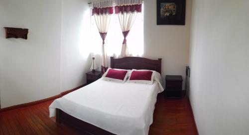 波帕扬Hotel Alcayata Colonial的卧室配有白色的床、红色枕头和窗户