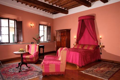卢奇尼亚诺Residenza d'Epoca Il Cassero的一间卧室配有粉红色的床和两把椅子