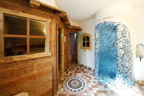 坎皮泰洛迪法萨Alpenhotel Panorama的房屋内带玻璃淋浴间的浴室
