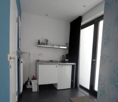 ReuverHet blauwe huis的白色的厨房设有水槽和窗户