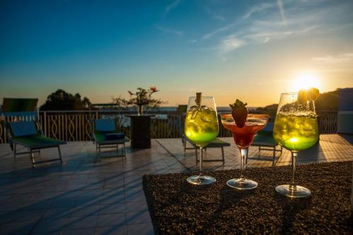 切特拉罗Hotel La Carruba的坐在桌子上,一边欣赏日落,一边享用三杯酒