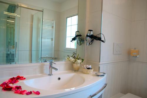 利尼亚诺萨比亚多罗拉格雷塔酒店的浴室设有水槽、镜子和红色玫瑰