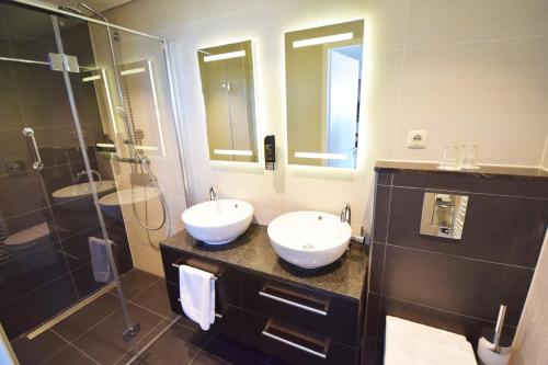 栋堡北海酒店的一间带两个水槽和玻璃淋浴间的浴室