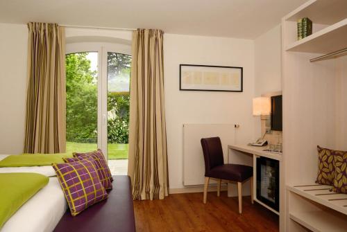 沃尔特湖畔佩莎赫达斯豪普特曼旅馆的配有一张床、一张书桌和一扇窗户的酒店客房